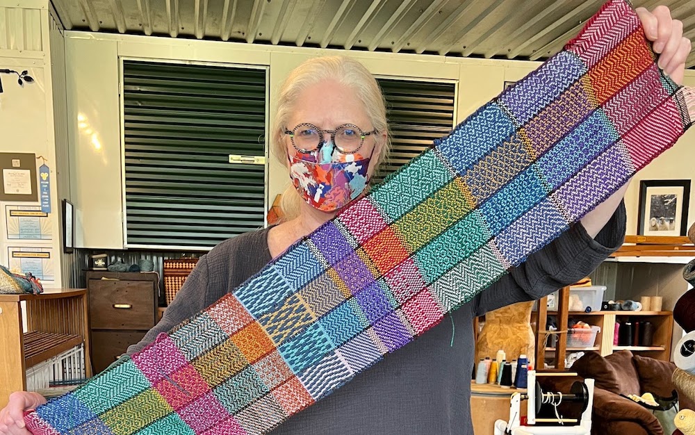 Patti holding a long narrow weaving sample of patterns